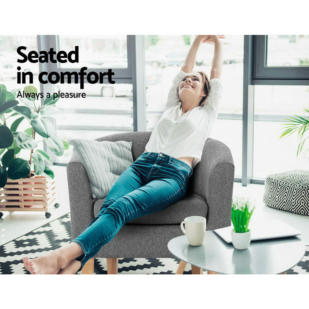 Woman lounging in grey fabric barrel armchair with legs over arm in modern room, text: Seated in comfort, Always a pleasure