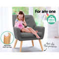 Child seated in grey fabric button-tufted armchair, 