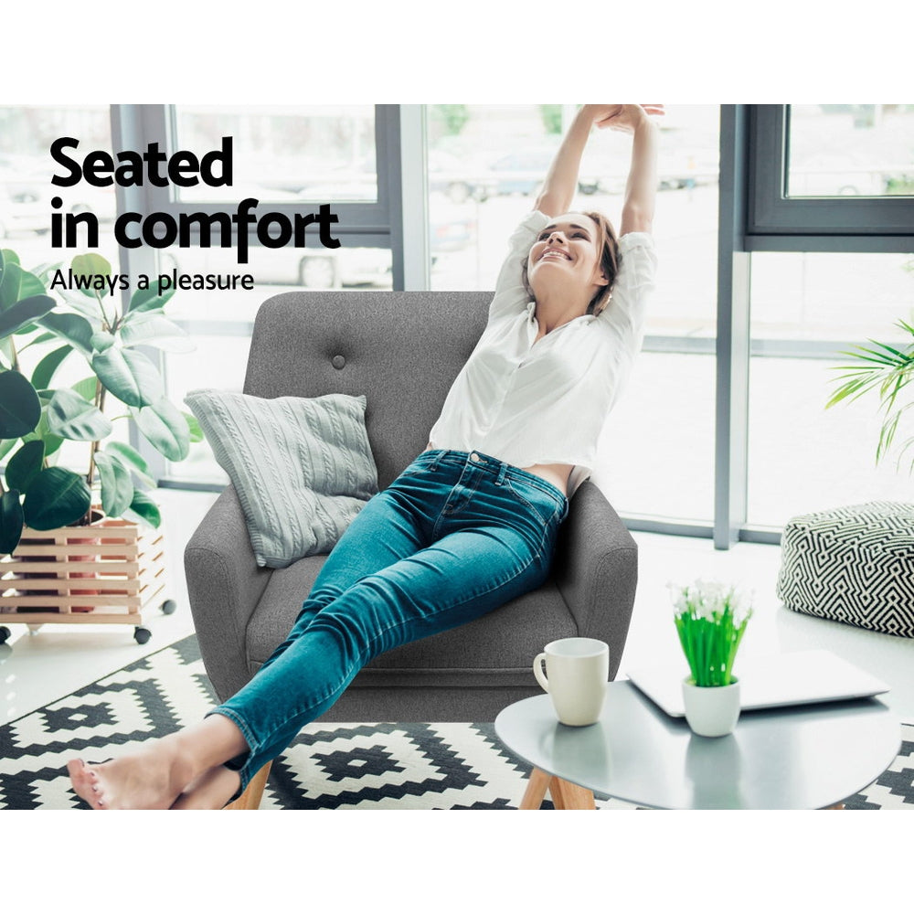Woman seated sideways in grey fabric button-tufted armchair in bright room, arms raised, "Seated in comfort" text overlay
