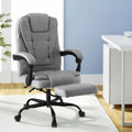 Grey fabric high-back office chair with footrest extended in lifestyle home office setting near white desk