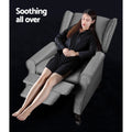 Grey fabric wingback recliner in fully reclined position with woman seated and footrest extended, Soothing all over text