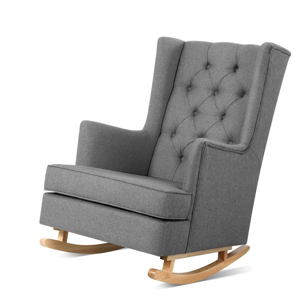 Grey fabric wingback rocking chair with button-tufted back and natural wood runners, angle view on white background