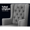 Grey fabric rocking chair close-up of diamond button-tufted wingback against dark background, Tufted wingback text