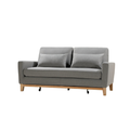 Three-quarter angle view of grey fabric sofa bed with two scatter pillows and wood legs with casters on white background