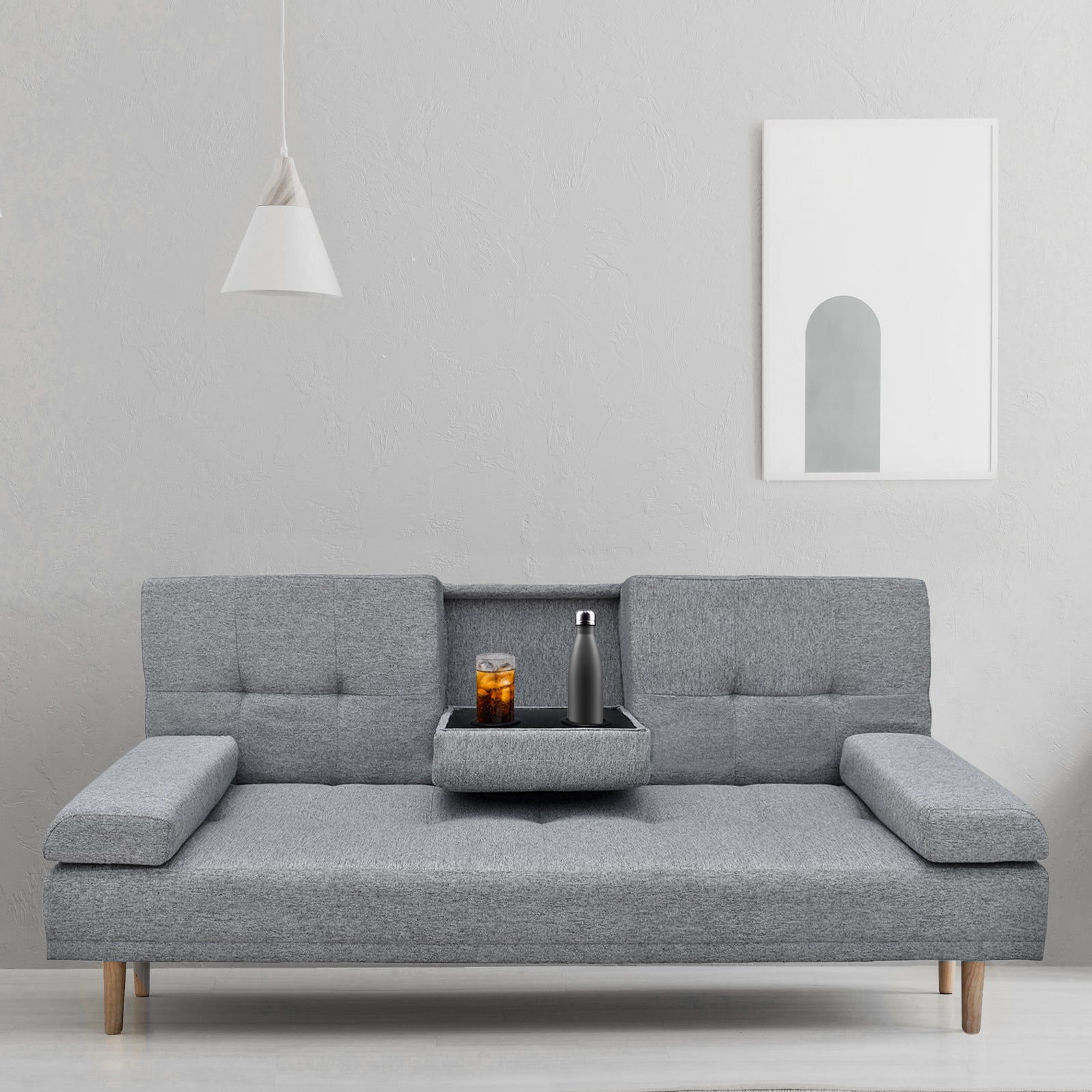 Grey fabric sofa bed in minimal room with centre cup holder tray open holding iced drink and water bottle