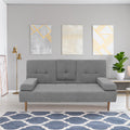 Grey fabric sofa bed in living room with gold geometric wall art, gold floor lamp and patterned rug