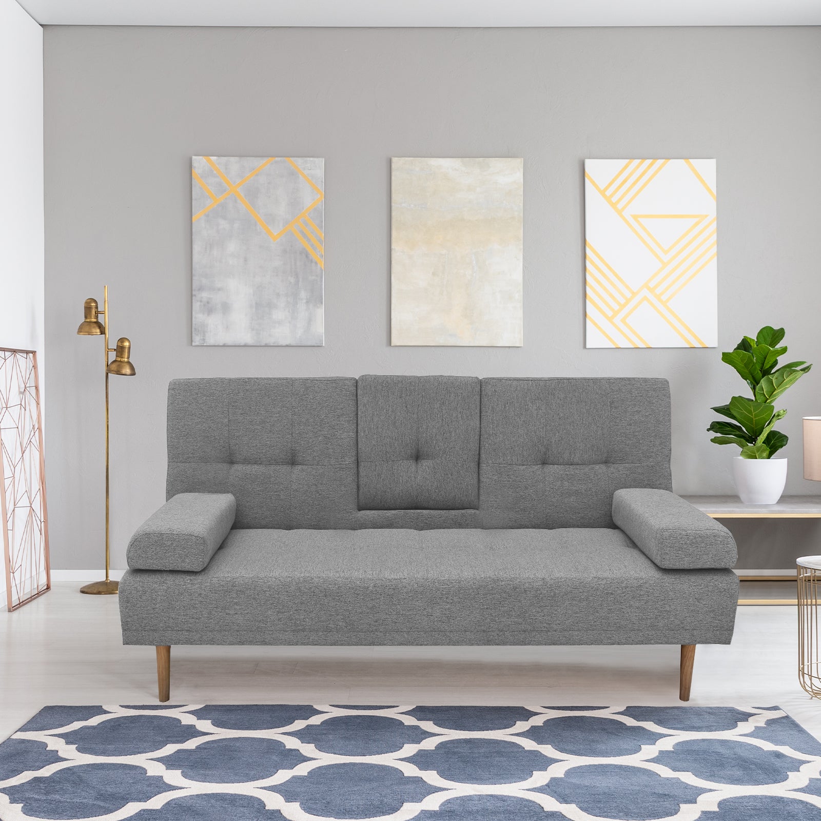 Grey fabric sofa bed in living room with gold geometric wall art, gold floor lamp and patterned rug