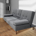 Grey fabric sofa bed partially reclined in room with herringbone wood floor and grey bookshelf