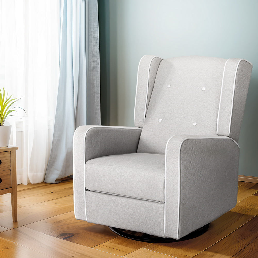 Light grey fabric wingback swivel recliner with white piping and three buttons, on timber floor with curtained window