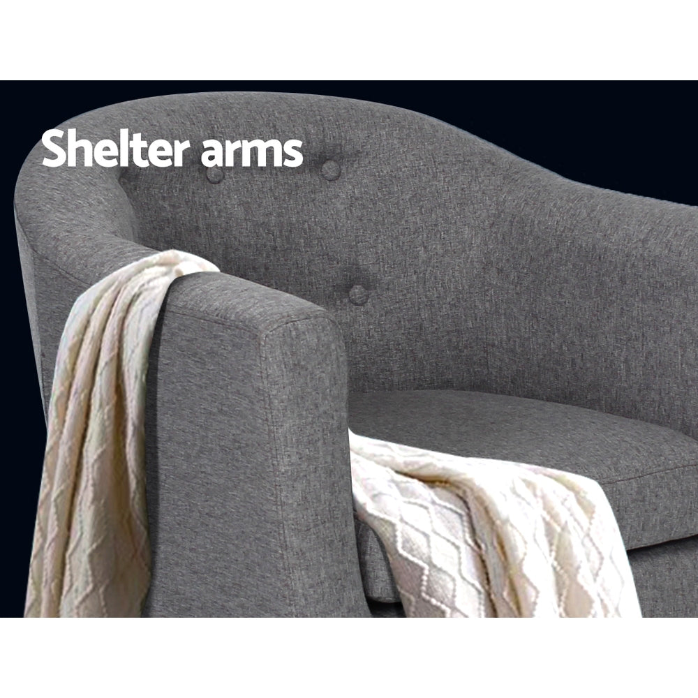 Grey fabric tub armchair close-up showing button-tufted back and shelter arms with cream throw draped, Shelter arms text