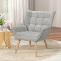 Light grey fabric grid-tufted wingback armchair in lifestyle room with wooden side table, rug and sheer curtains