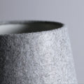 Close-up of top of light grey felt lamp shade showing dark interior and tapered textured exterior