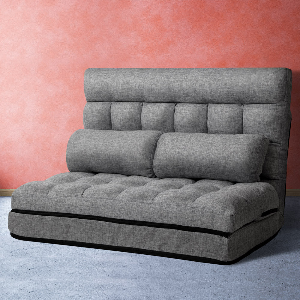 Grey linen 2-seat floor lounger upright against coral textured wall with two bolster pillows and headrest roll