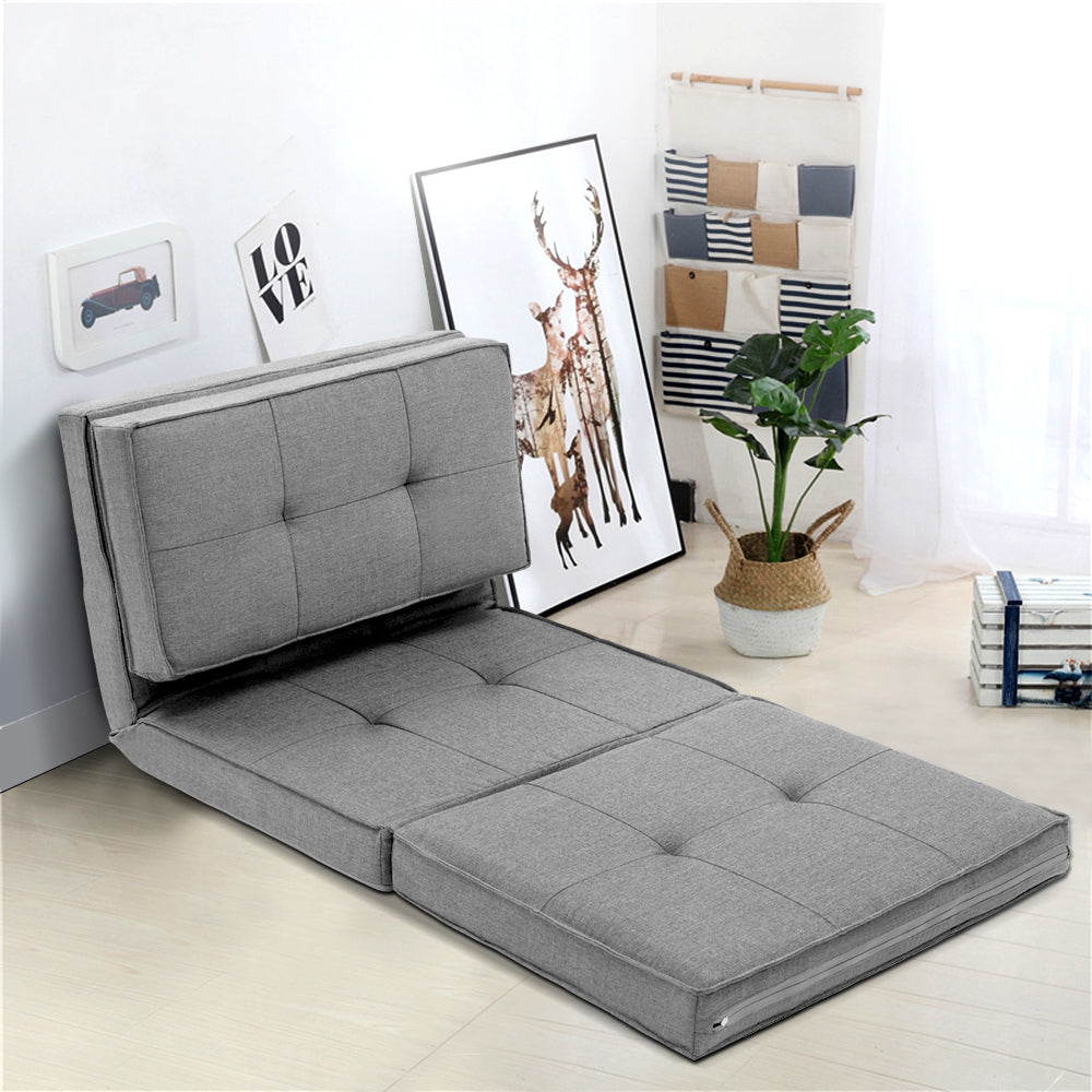 Grey linen foldable floor lounger in semi-reclined position in room with love art print and plant