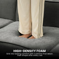 Dark grey modular L-shaped sofa in sunlit living room with green curtains, timber floor and patterned throw on ottoman