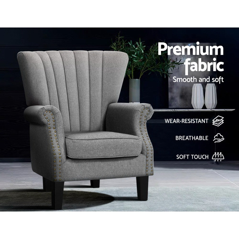 Grey fabric nailhead wingback armchair in dark lifestyle room, badges: Premium fabric, Wear-resistant, Breathable, Soft touch