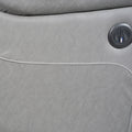 Close-up of grey electric recliner sofa arm showing round black electric recline button