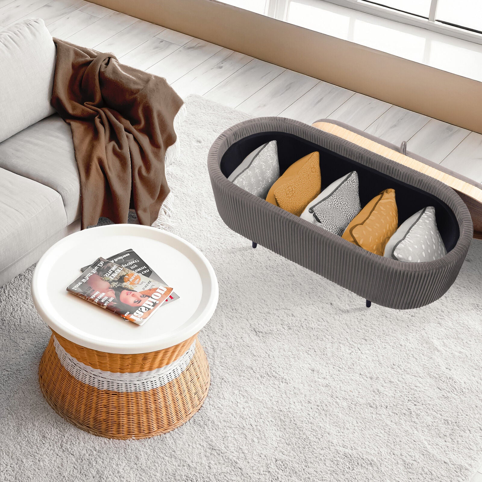Grey ribbed oval ottoman with lid open showing cushions stored inside, styled in living room with rattan coffee table on rug