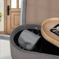 Round grey ribbed ottoman in entryway with lid open revealing stored handbag, keys and wallet on wood lid surface