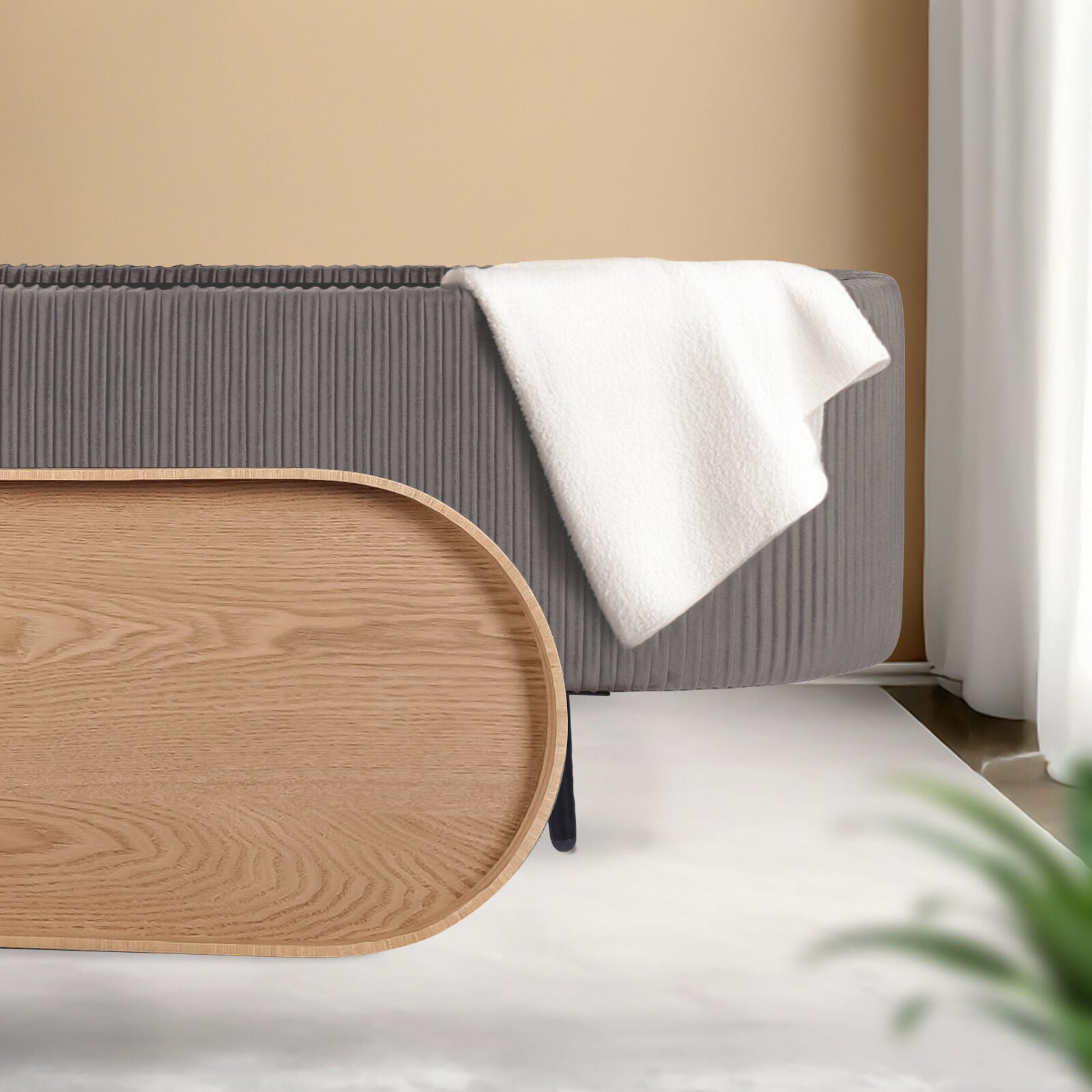 Grey ribbed oval ottoman with natural wood oval lid leaned against side and white throw draped over top