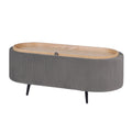 Oval storage ottoman with grey ribbed fabric, natural wood lid with handle and black tapered legs on white background