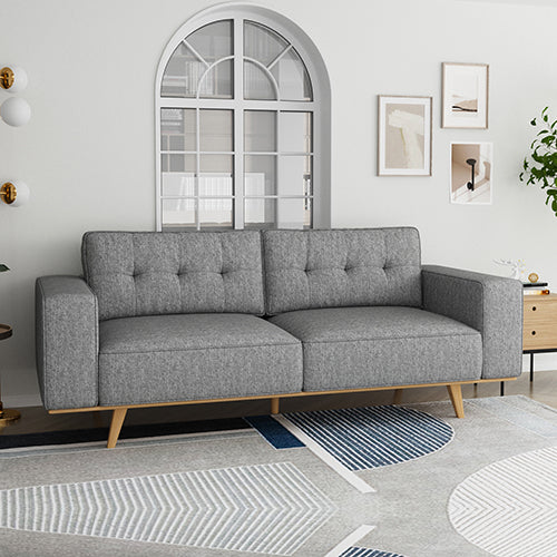 Grey tufted 3-seater sofa with natural wood legs in white living room with arch window lifestyle shot