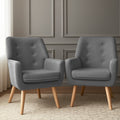 Pair of dark grey button-tufted fabric armchairs on patterned rug, grey panelled wall background