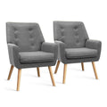 Pair of dark grey button-tufted fabric armchairs with natural wood legs, three-quarter view on white background