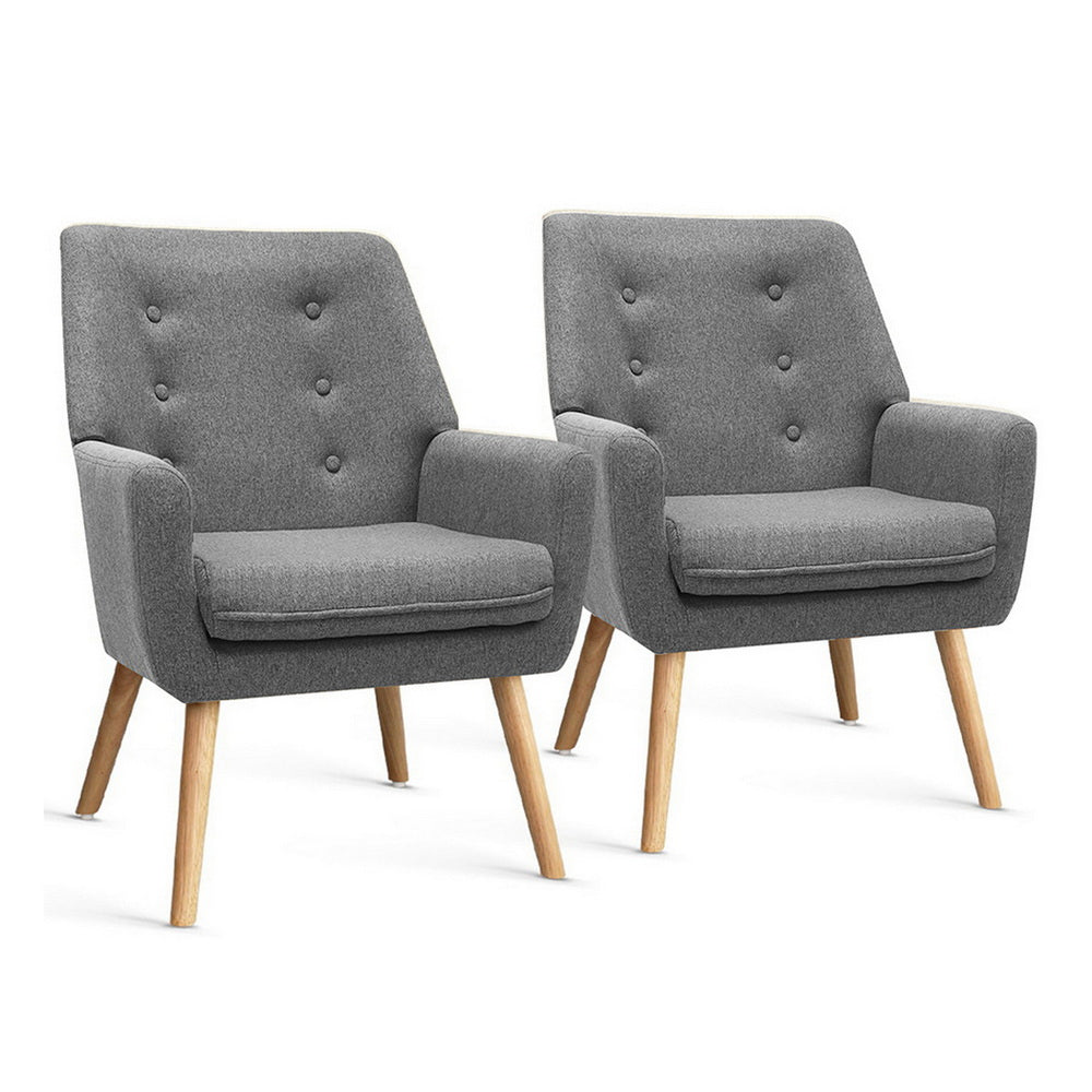 Pair of dark grey button-tufted fabric armchairs with natural wood legs, three-quarter view on white background