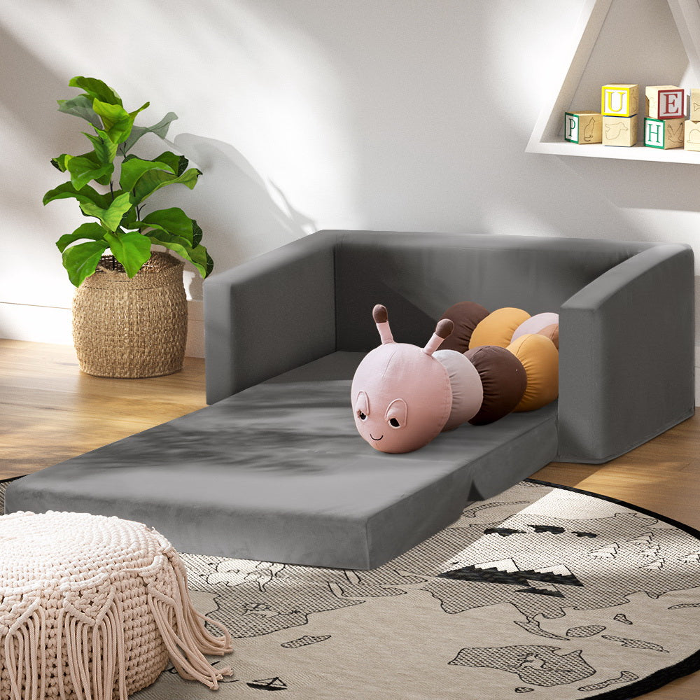 Grey velvet kids sofa bed fully extended flat in kids room with colourful worm toy and bookshelf