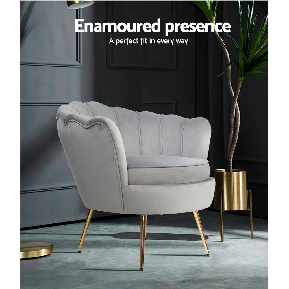 Light grey velvet scallop shell armchair with gold legs in dark moody room with plant in gold pot, Enamoured presence text