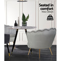 Grey velvet scallop shell armchair rear view at round marble table with 150kg max load badge in white panelled room