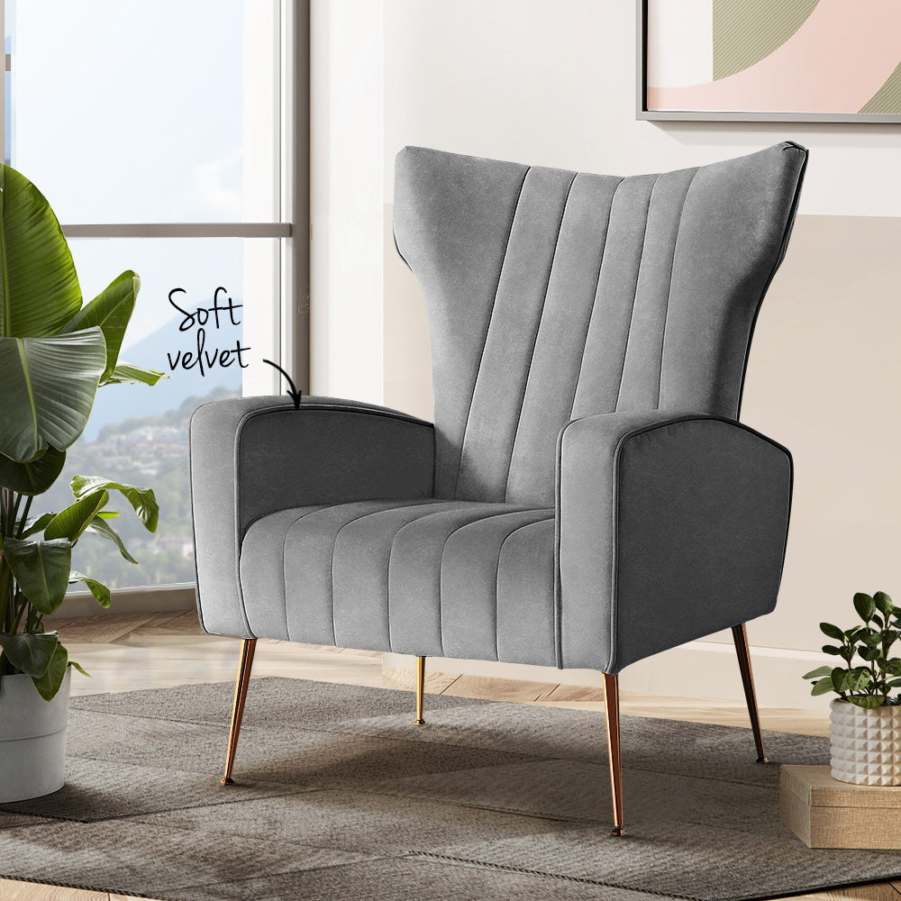 Grey velvet wingback armchair in lifestyle room setting with large tropical plant and Soft velvet text callout
