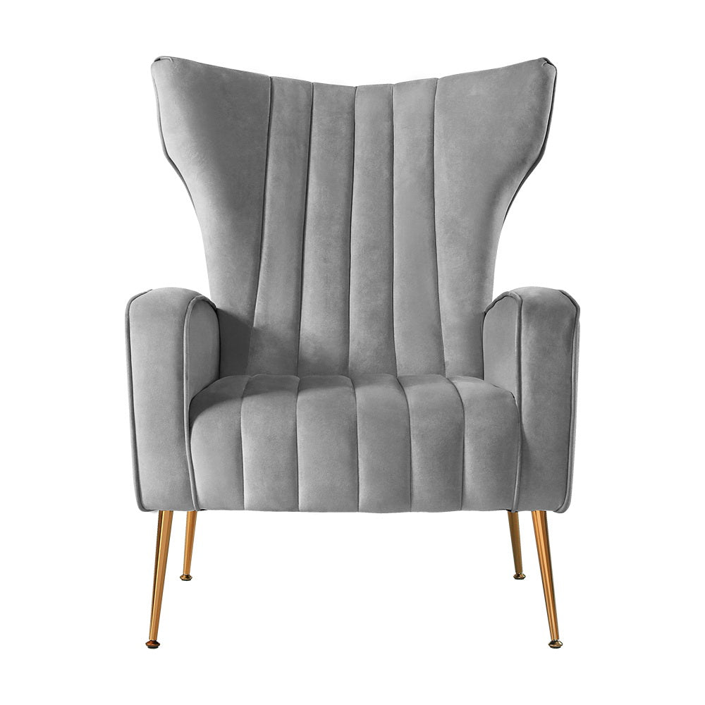 Grey velvet wingback armchair with tall winged back and vertical channel stitching front view on white background
