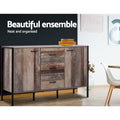 Industrial buffet with reclaimed wood finish in dining room with dark feature wall, orange plates on top, rose vase beside