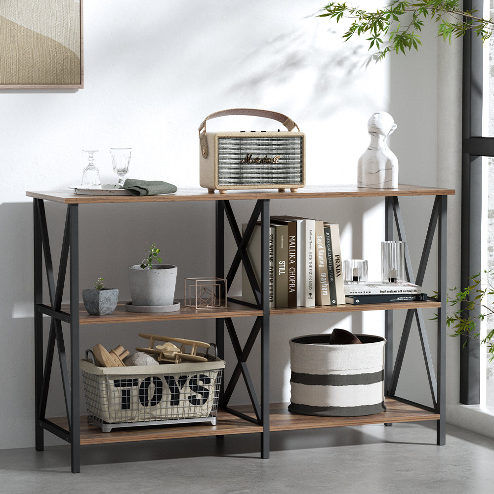 Three-tier industrial console table with dark walnut shelves and black X-frame sides, styled with books, speaker, plants