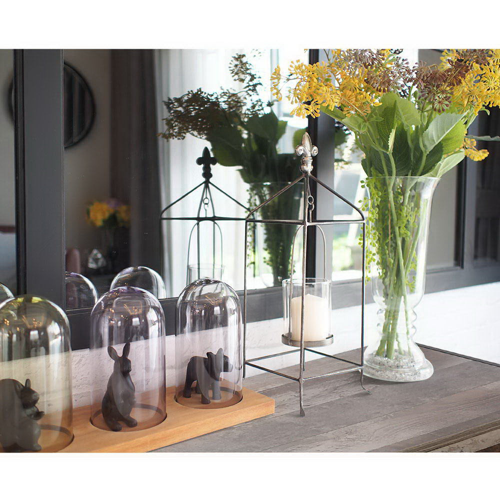 Industrial console table top styled with glass cloches, animal figurines, cage candle lantern and yellow flower vase