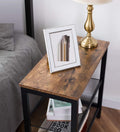 Industrial side table close-up in bedroom with photo frame and brass lamp on rustic wood top, books on shelf