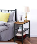 Industrial side table in bedroom beside bed with brass lamp and frame on top, books and basket on mesh shelves