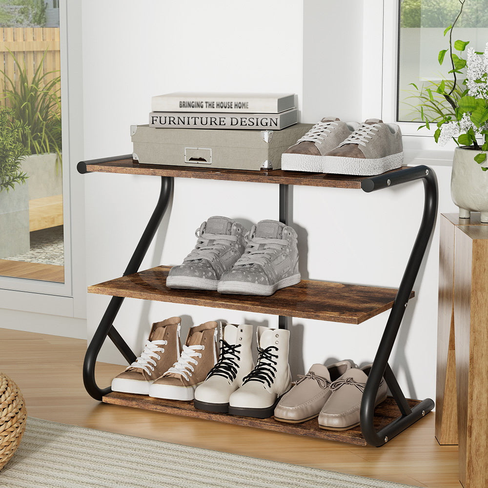 Three-tier industrial shoe rack with rustic brown shelves and black curved Z-frame, loaded with shoes in room