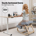 Woman seated on grey kneeling rocker chair at standing desk, 120kg capacity badge, sturdy bentwood frame infographic