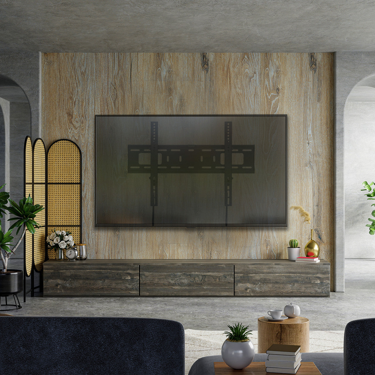 Fixed TV wall bracket lifestyle in industrial room with TV on wood-panel wall grey TV unit drawers plants and rattan screen