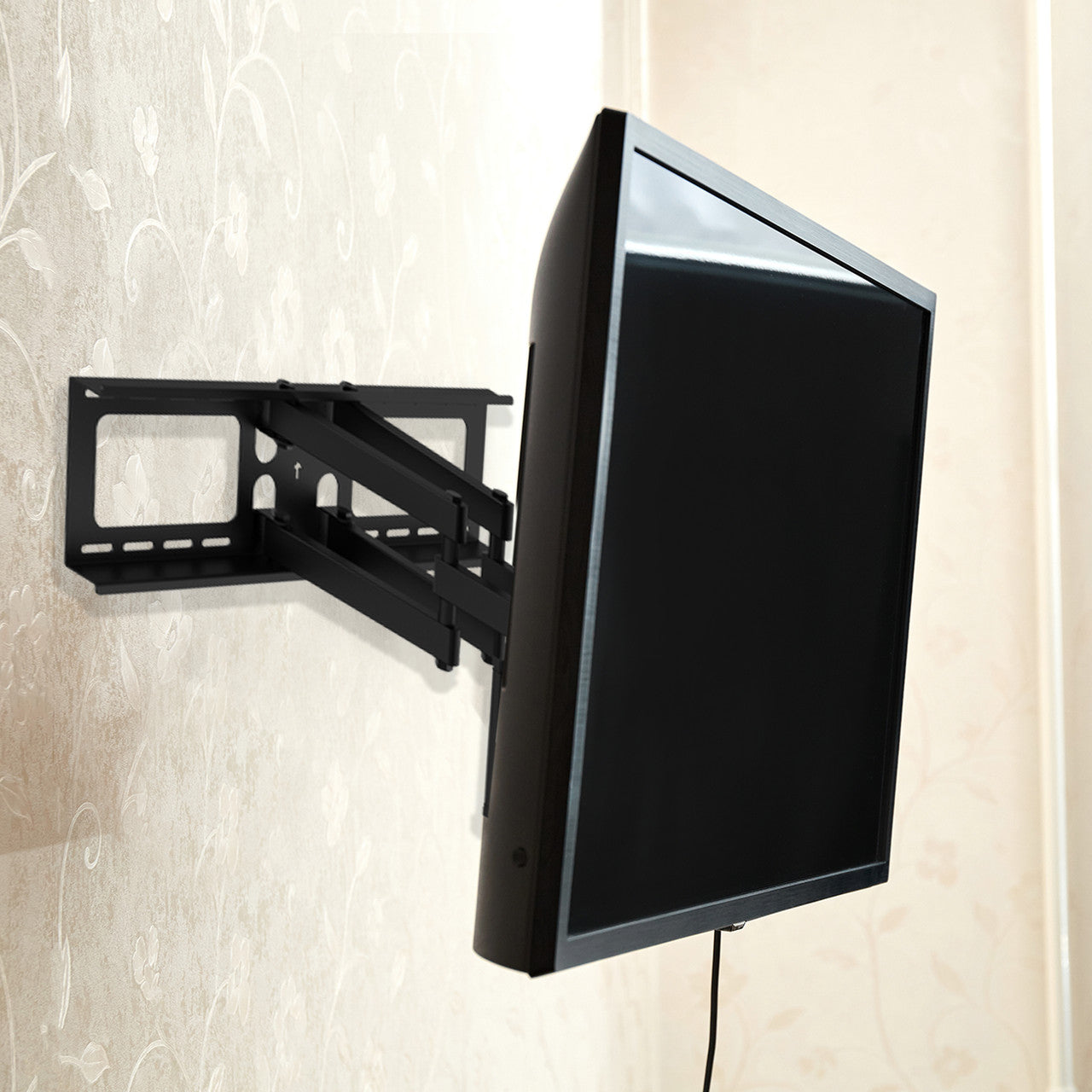 Full-motion TV wall bracket with TV swiveled sideways in room with floral wallpaper showing extended arm