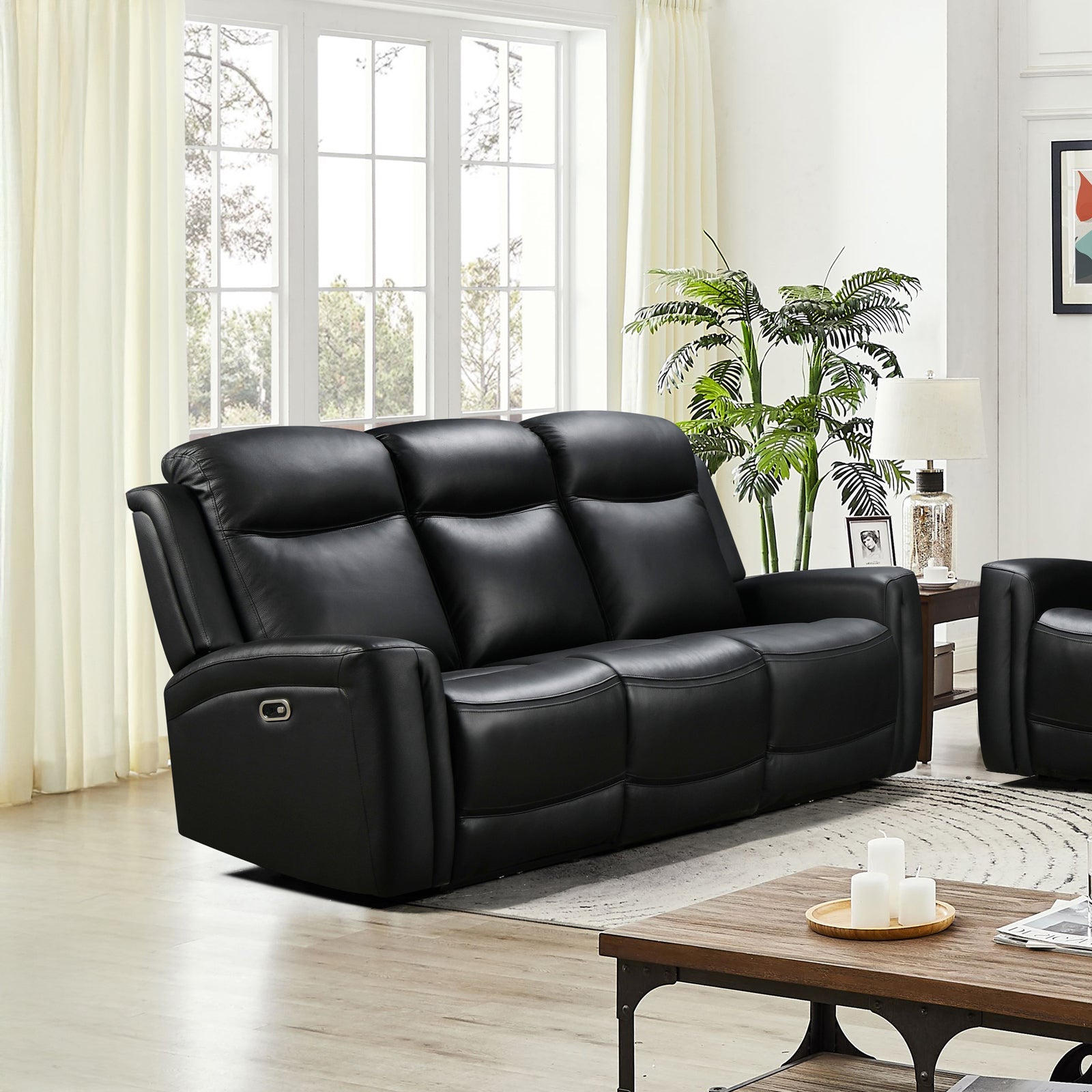 Black leather 3-seat power recliner sofa in living room with tall windows, indoor plant and side table