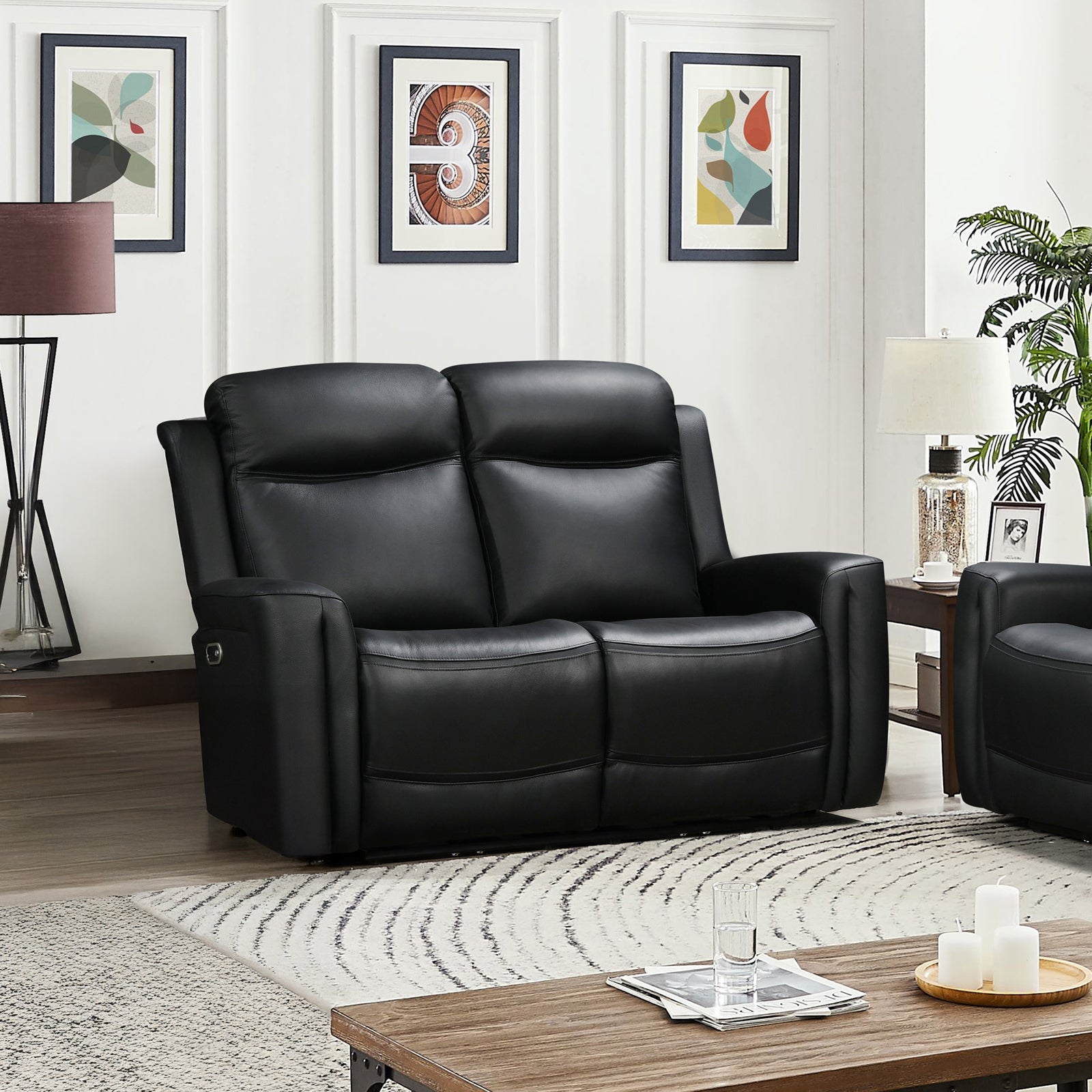 Black leather 2-seat power recliner loveseat in styled living room with framed artwork, plant and lamp