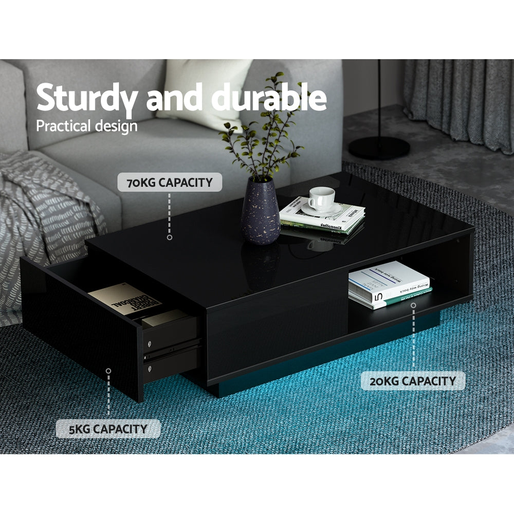Black high-gloss LED coffee table in living room showing 70KG top, 20KG shelf and 5KG drawer capacity