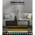 Black high-gloss coffee table with warm LED underglow light in a living room, with text reading Brilliant effects, four