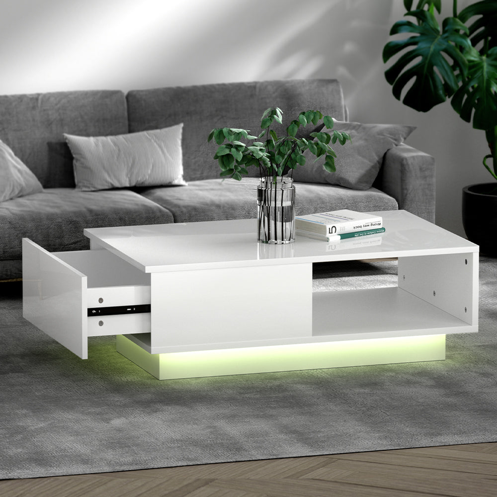White high-gloss LED coffee table with a drawer pulled open on the left and open shelf on the right, glowing green LED base
