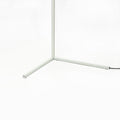 Close-up of white square-section tripod base of LED floor lamp with black power cord on white background