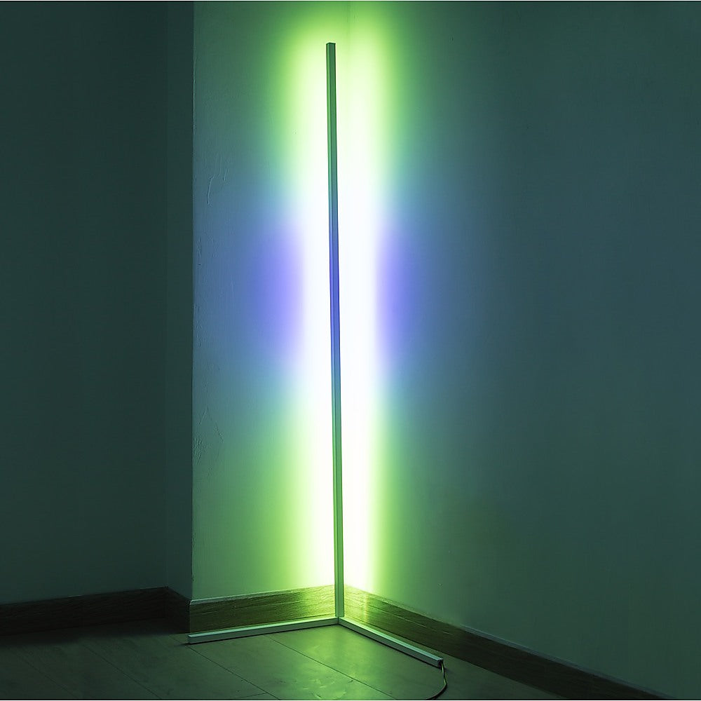LED corner floor lamp projecting green and purple gradient light onto dark room corner walls with T-bar base visible